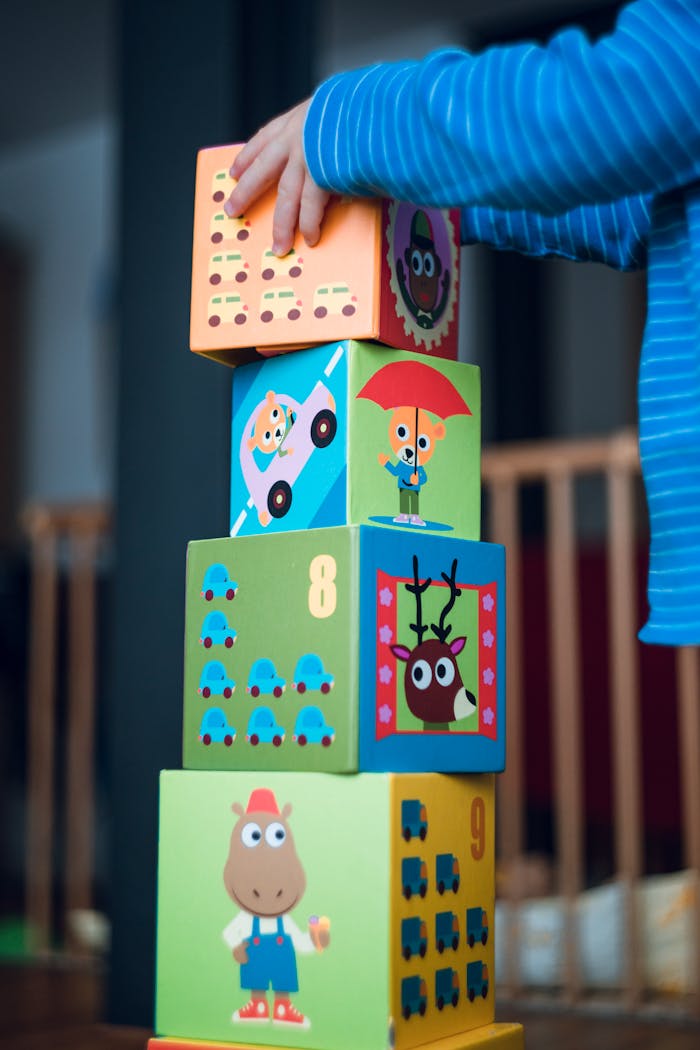 creative A child playing indoors, stacking colorful wooden toy blocks with joyful illustrations.