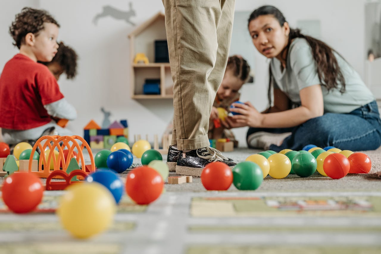 our-story Children and a teacher playing with toys in a kindergarten setting indoors.