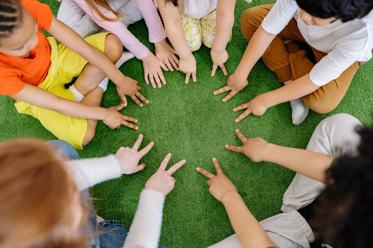 why-choose-us Children sitting in a circle playing fun team games on artificial grass.